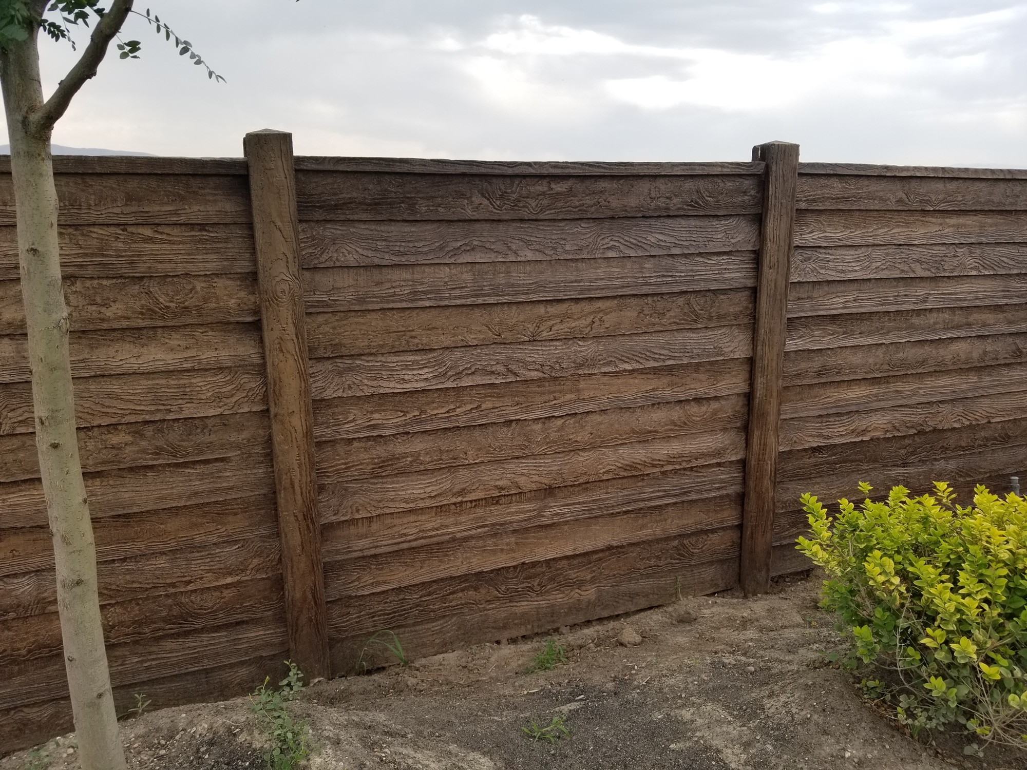 Concrete privacy fence with a wood-grain finish